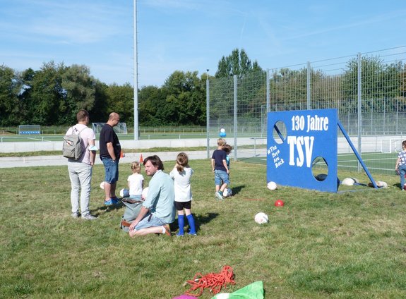 Kinder und Erwachsene vor einer blauen Torwand mit der Aufschrift 130 Jahre TSV