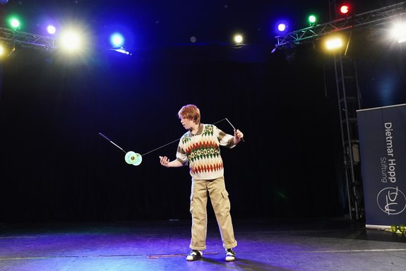 In einer Zirkusmanege jongliert ein Junge mit einem Diabolo.