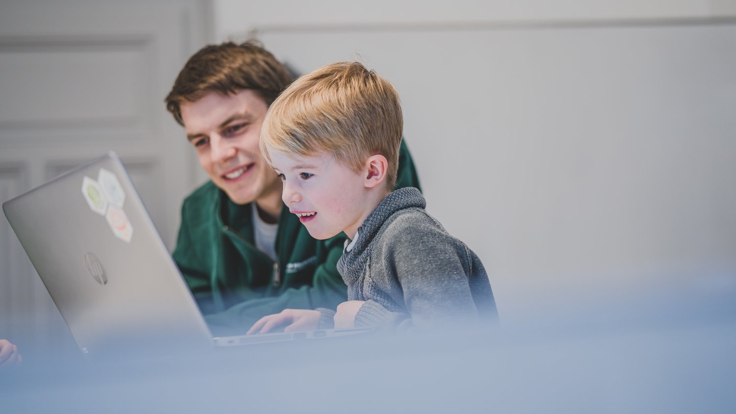 Junger Mann und Kind blicken gemeinsam auf den Monitor eines Laptops